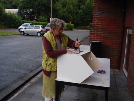 Els bouwt aan een houten huissculptuur buiten